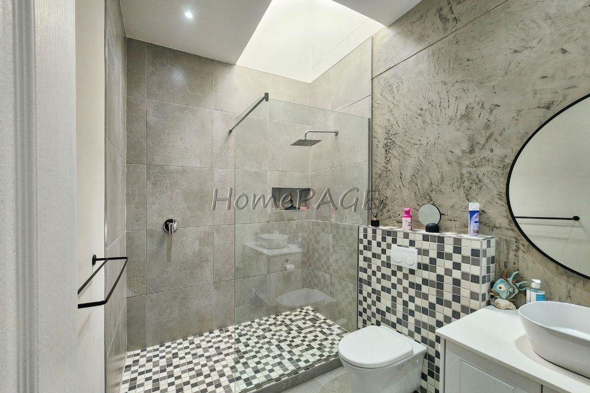 Modern bathroom featuring a walk-in shower with glass screen, wall-mounted toilet, and a contemporary vanity with a vessel sink.