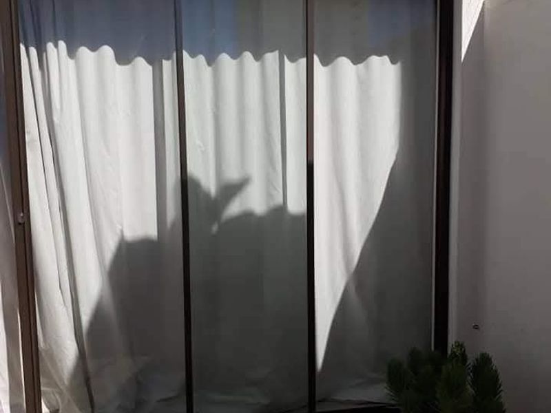 A paved patio area featuring a large sliding glass door entrance and perimeter electric fencing.