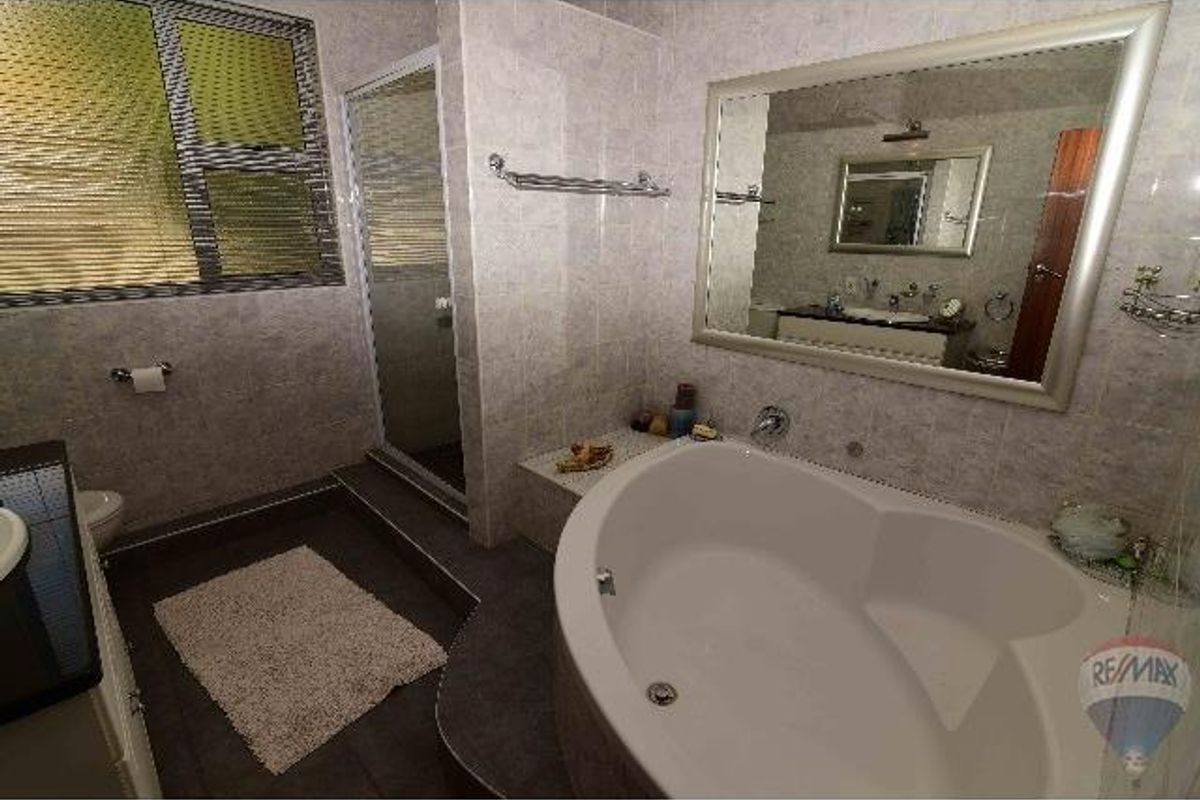 A well-appointed bathroom featuring a large corner soaking tub, a separate glass-enclosed shower, and a vanity with a large wall-mounted mirror.
