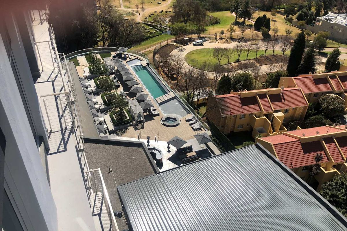 An elevated aerial view of the apartment complex pool area, featuring a lap pool, jacuzzi, and landscaped outdoor deck space.