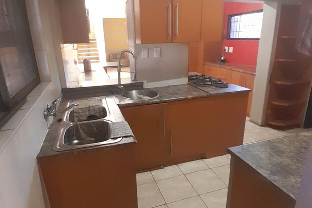 Functional kitchen featuring built-in cabinetry, laminate countertops, a double bowl sink, and a gas hob with tiled flooring.