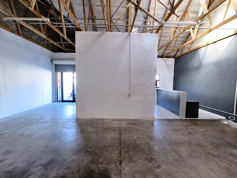 Spacious industrial open-plan unit featuring exposed timber roof trusses, polished concrete flooring, and a central partition wall with a built-in reception counter.