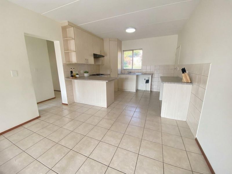 A functional kitchen featuring light-toned laminate cabinetry, tiled flooring, and a tiled backsplash, offering a clean and practical layout.