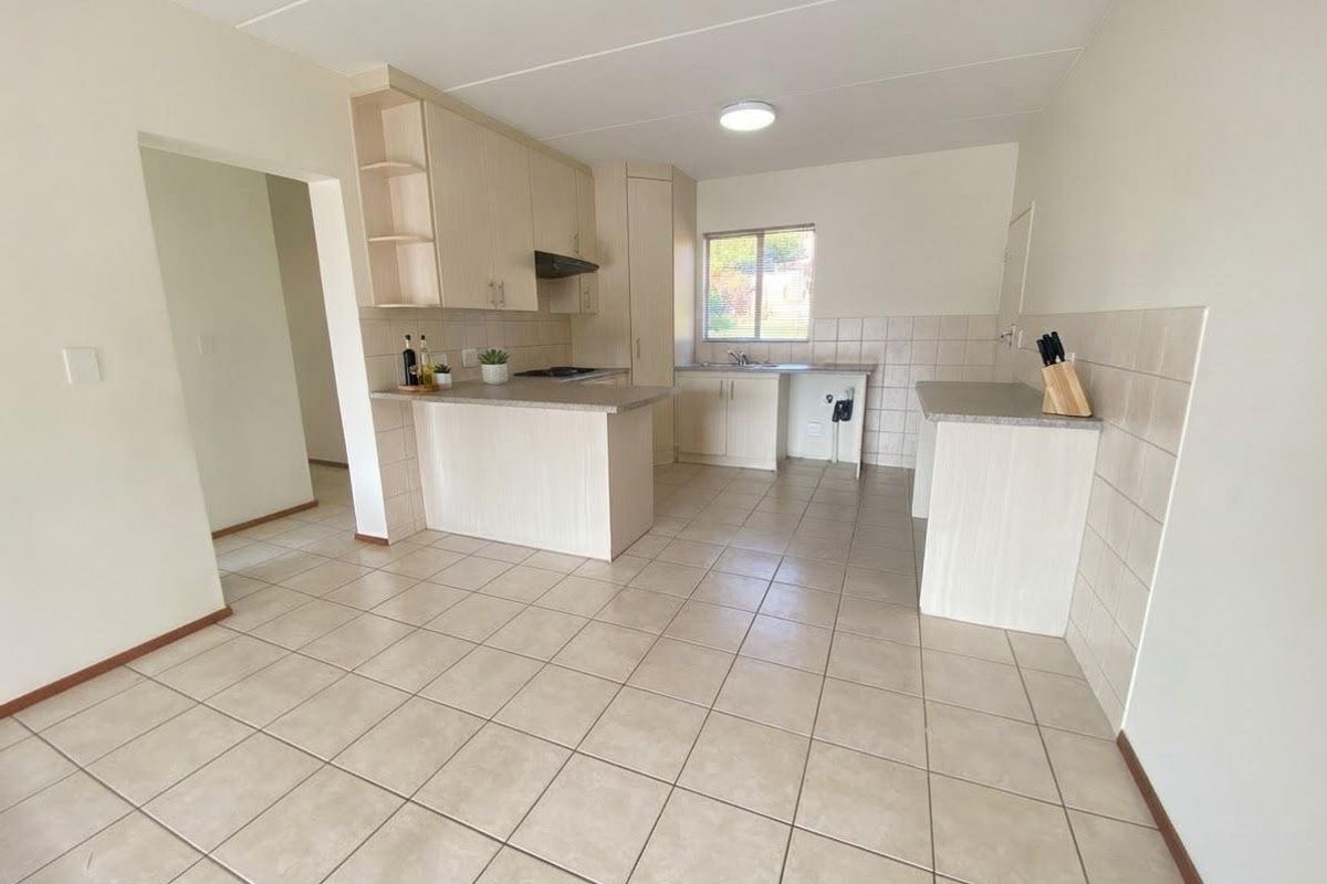 A functional kitchen featuring light-toned laminate cabinetry, tiled flooring, and a tiled backsplash, offering a clean and practical layout.