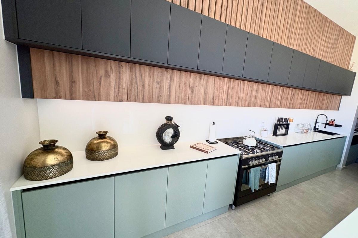 Modern kitchen featuring sleek matte cabinetry, wood-panelled wall accents, stone countertops, and a built-in gas stove with a contemporary design.