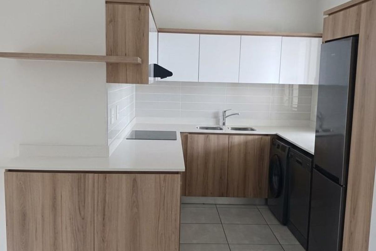 Modern kitchen featuring wood-grain and white cabinetry, stone countertops, subway tile backsplash, and integrated appliances with neutral floor tiling.