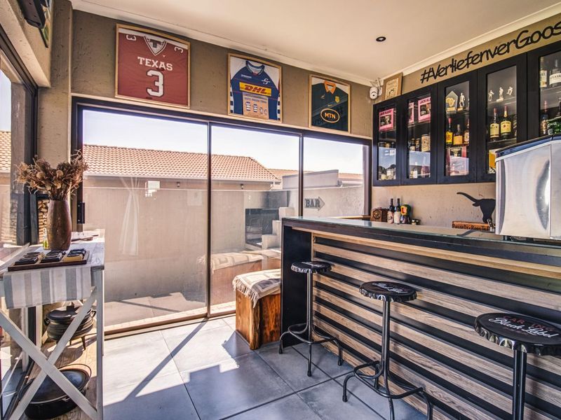A well-appointed indoor bar area featuring a custom built-in counter, glass display cabinetry, and large sliding doors opening to an outdoor patio space.