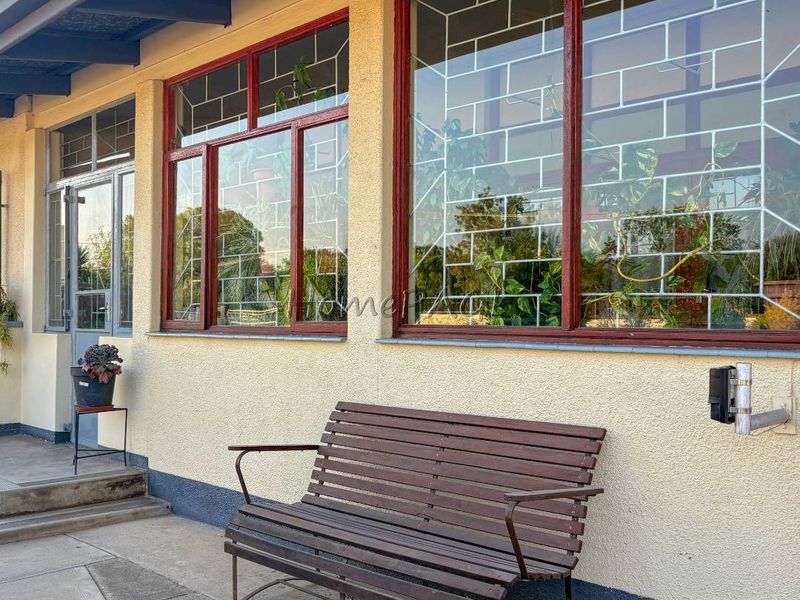 Front exterior view of the property featuring a concrete patio, stucco facade, and large windows with integrated security bars.