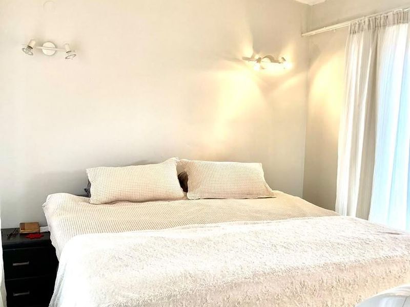 A comfortable bedroom featuring neutral wall tones, wall-mounted lighting, and window treatments, providing a functional and inviting space.
