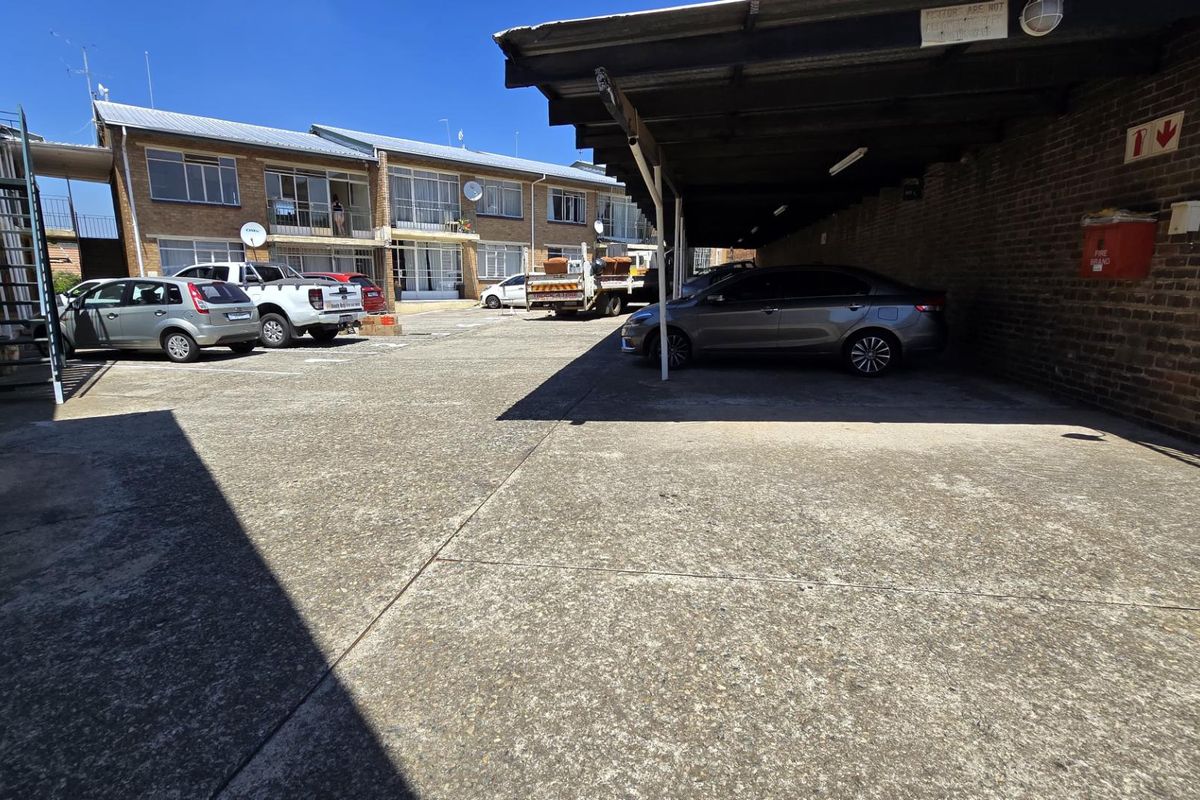 Exterior view of the apartment complex parking area featuring a covered carport structure and concrete driveway.