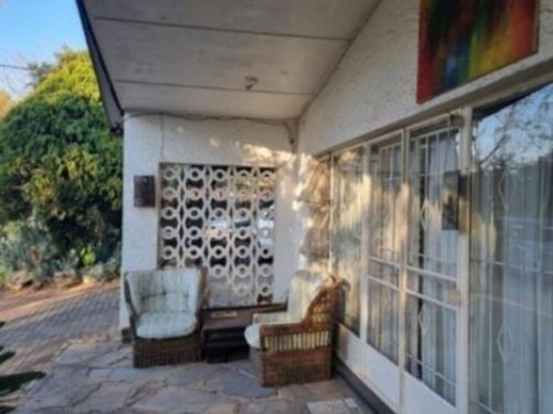 A covered patio area featuring stone paving, a decorative breeze block screen, and large sliding glass doors providing access to the cottage interior.
