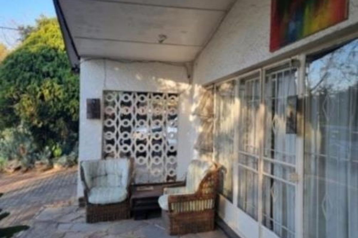 A covered patio area featuring stone paving, a decorative breeze block screen, and large sliding glass doors providing access to the cottage interior.