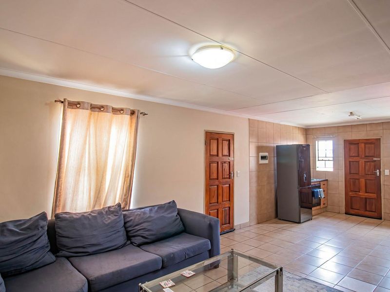 Open-plan living and kitchen area featuring tiled flooring, neutral walls, and functional built-in cabinetry, offering a versatile space for daily living.