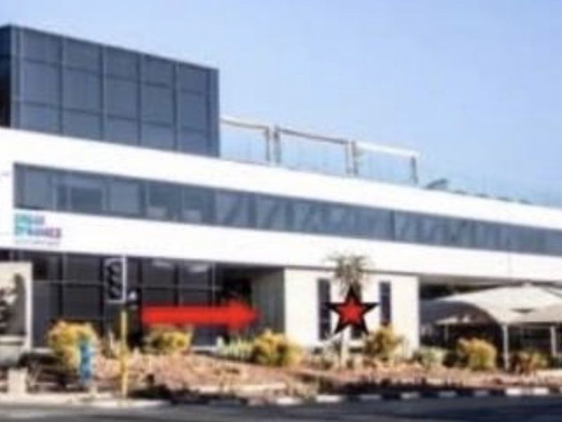 Modern multi-story office building featuring a glass facade and integrated covered parking area.