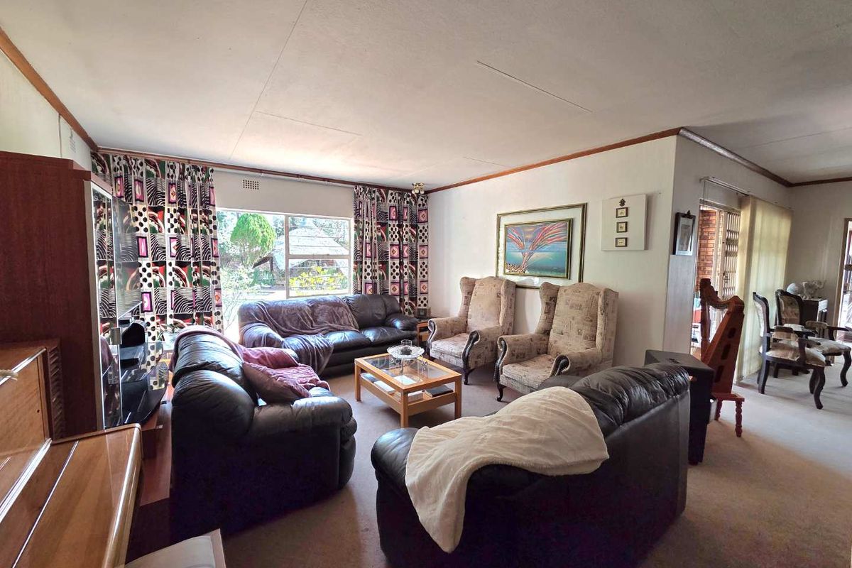 A spacious living room featuring carpeted flooring and a large window that allows for natural light, providing a comfortable and functional family area.