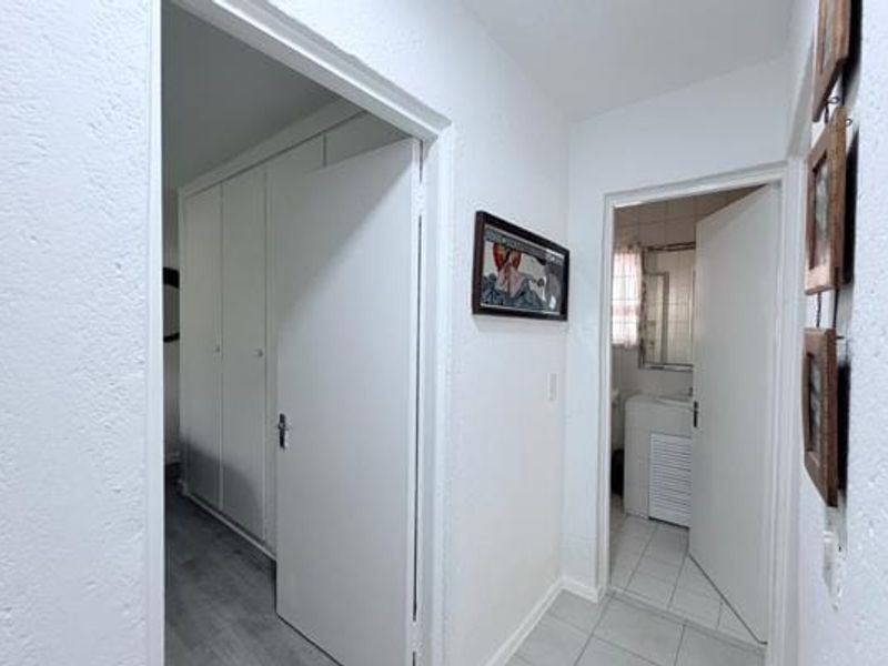 A functional hallway connecting living spaces, featuring built-in cupboards for storage and tiled flooring throughout.