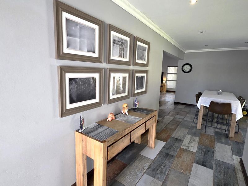 An open-plan living and dining area featuring modern multi-toned tiled flooring, recessed downlighting, and neutral wall finishes.