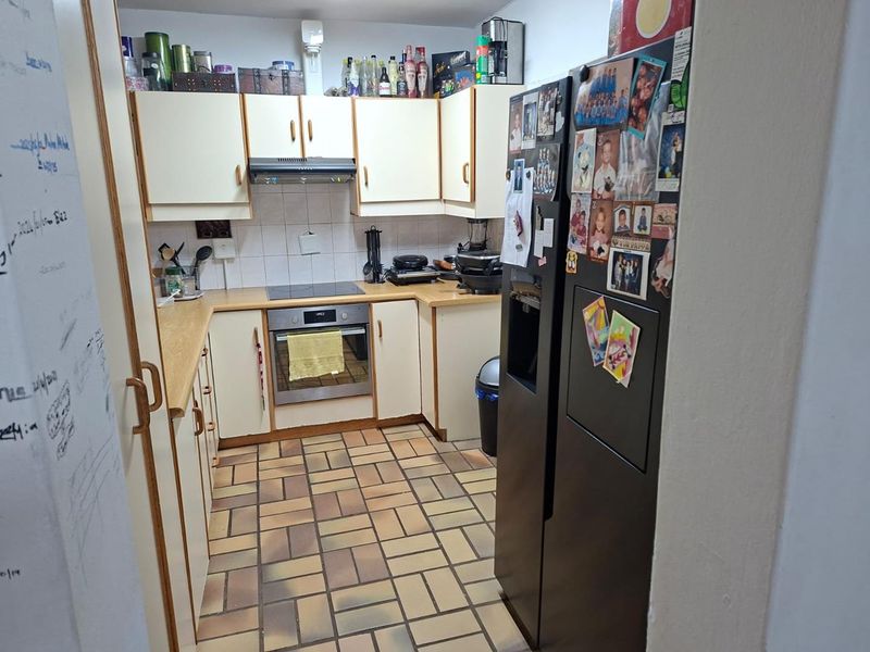 A functional kitchen featuring built-in cabinetry, laminate countertops, an integrated oven and hob, and durable tiled flooring.