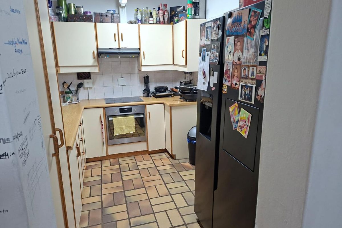 A functional kitchen featuring built-in cabinetry, laminate countertops, an integrated oven and hob, and durable tiled flooring.