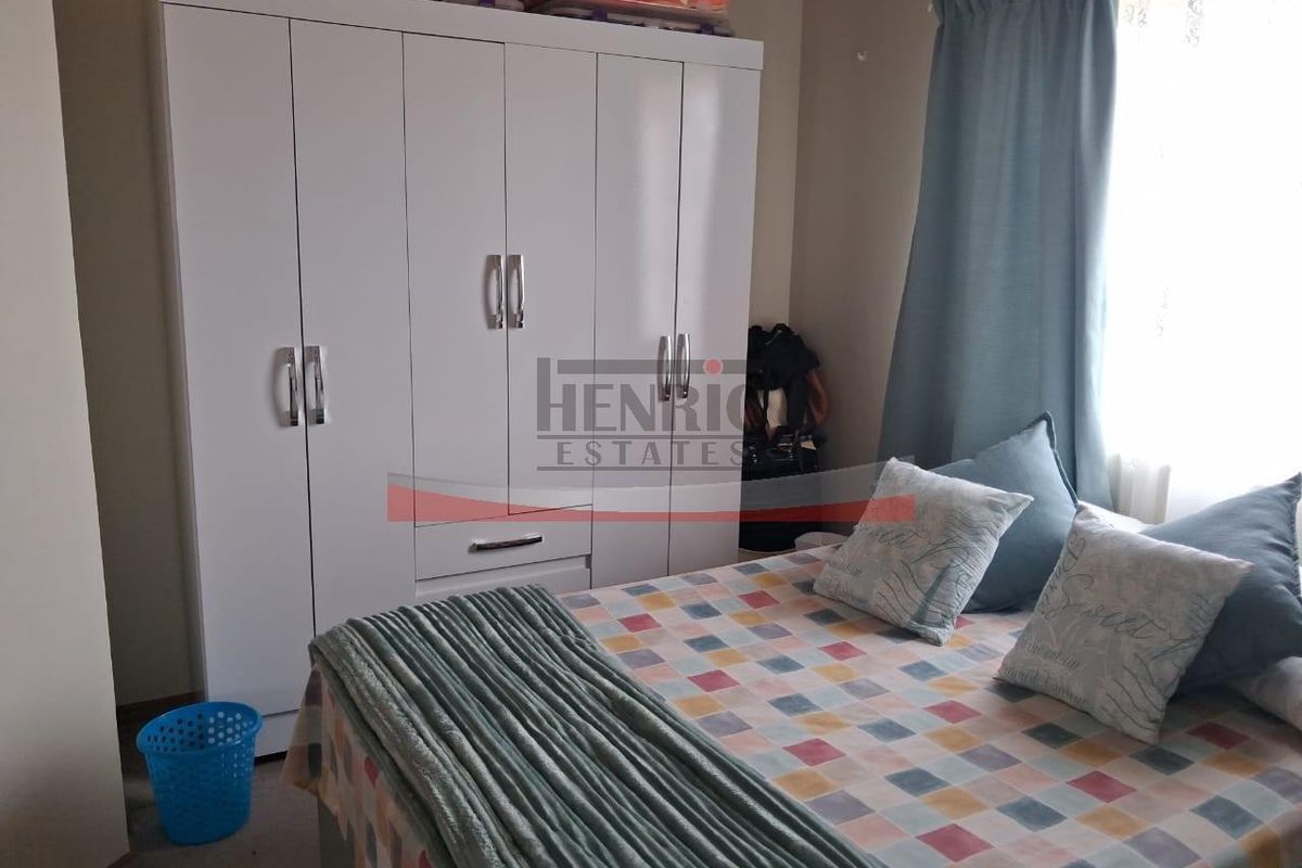 A bedroom featuring a white built-in wardrobe and natural light from the window.