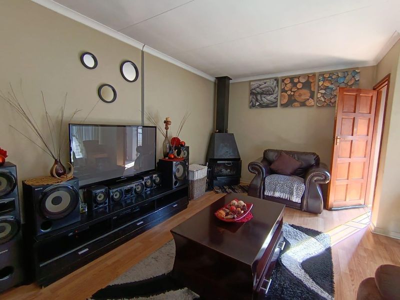A cozy living room featuring laminate flooring, a built-in wood-burning fireplace, and coved ceiling details.