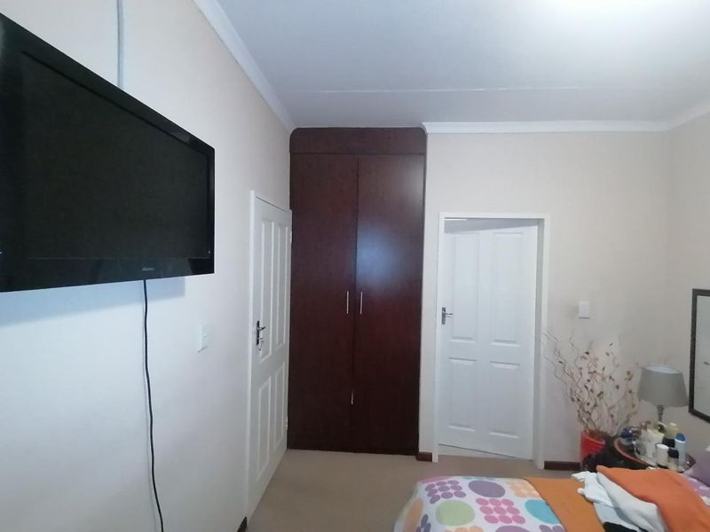 A bedroom featuring a dark wood built-in wardrobe, white internal doors, and neutral wall finishes.