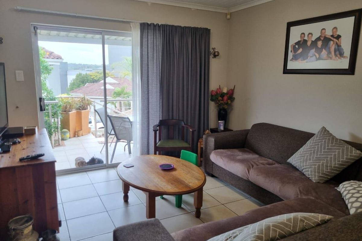 A comfortable living room featuring tiled flooring and large sliding glass doors that provide direct access to an outdoor patio area.