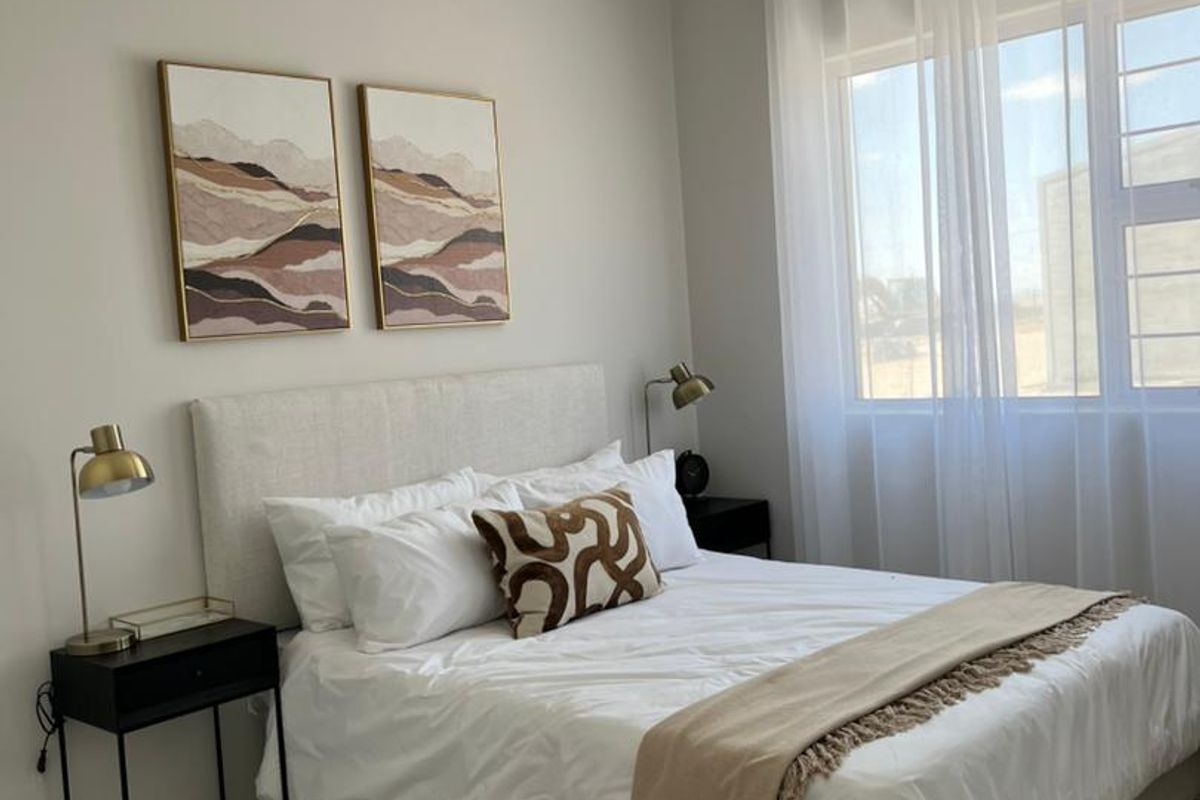 A well-maintained bedroom featuring neutral wall tones, tiled flooring, and a high tongue and groove ceiling, providing a bright and comfortable living space.