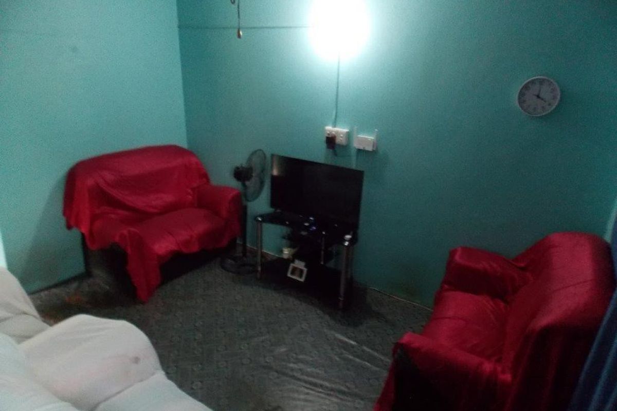 A small living room area featuring painted walls and basic electrical infrastructure, currently furnished with seating.