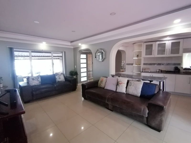 Open-plan living area featuring tiled floors, recessed lighting, and a modern kitchen with a breakfast bar and integrated cabinetry.