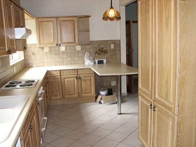 A functional kitchen featuring wooden cabinetry, laminate countertops, tiled backsplash, and built-in appliances, offering a classic layout with potential for modern updates.