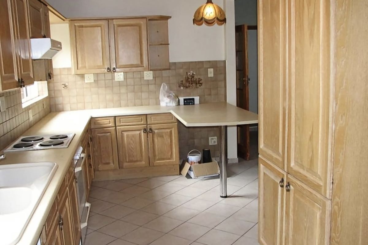 A functional kitchen featuring wooden cabinetry, laminate countertops, tiled backsplash, and built-in appliances, offering a classic layout with potential for modern updates.