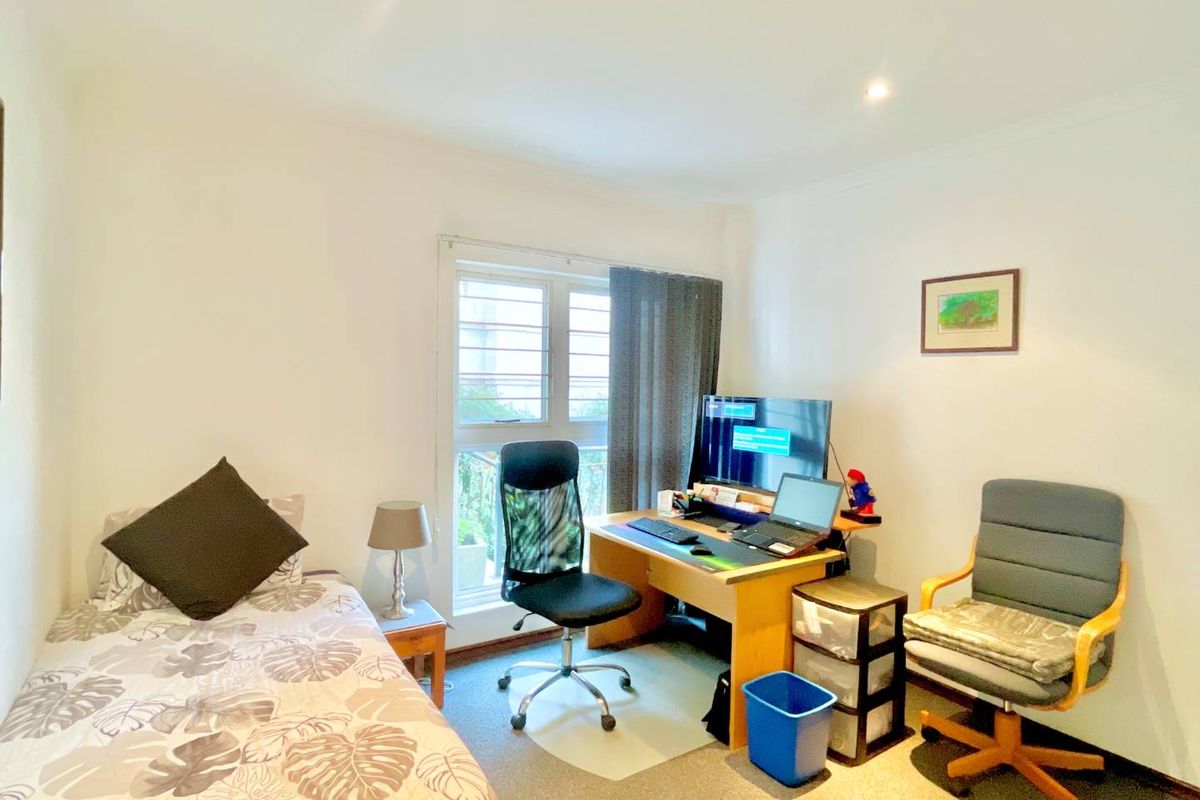 A functional bedroom featuring a window with security bars, neutral wall finishes, and carpeted flooring, suitable for use as a bedroom or home office.