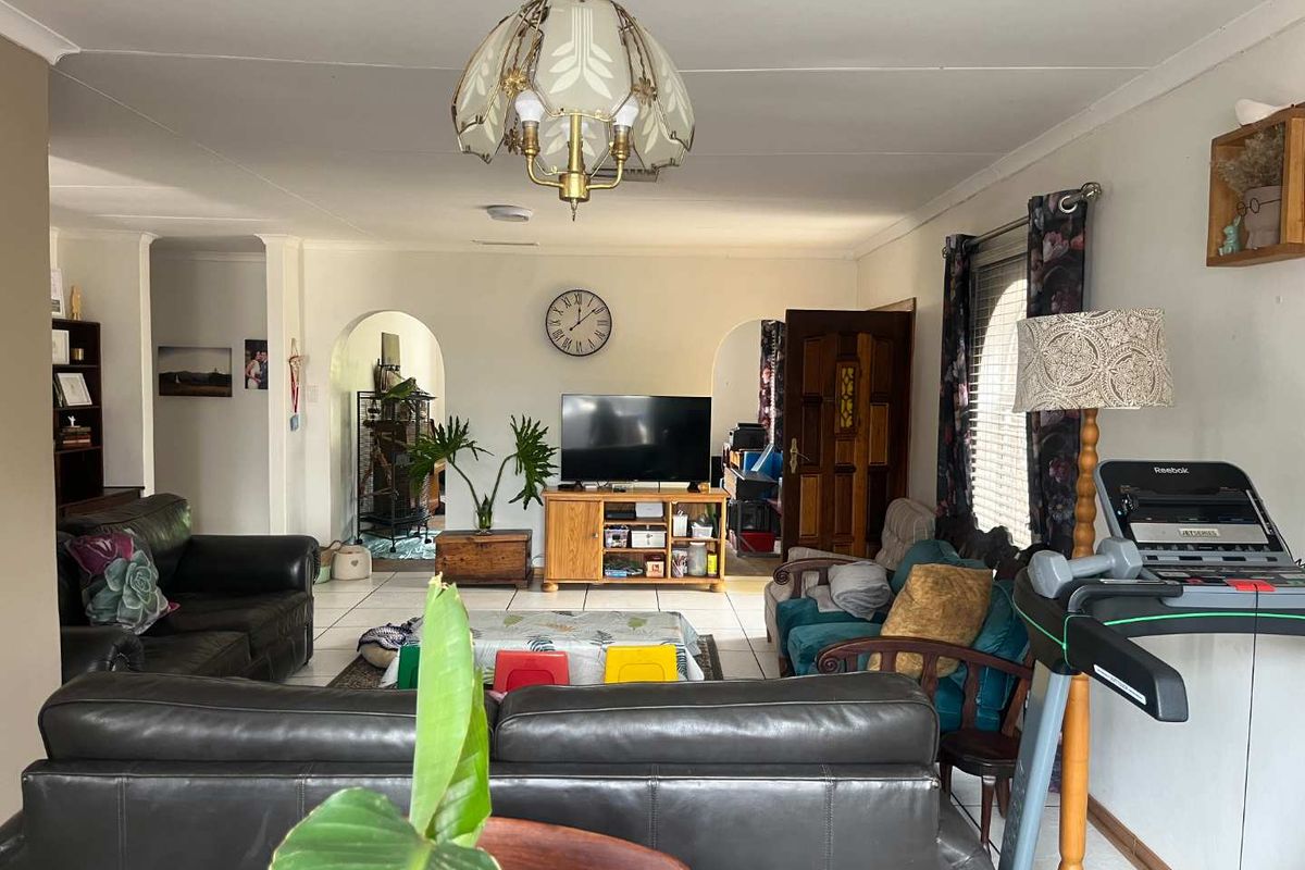 Spacious living room featuring tiled flooring, arched architectural doorways, and coved ceilings, offering a functional layout with natural light.