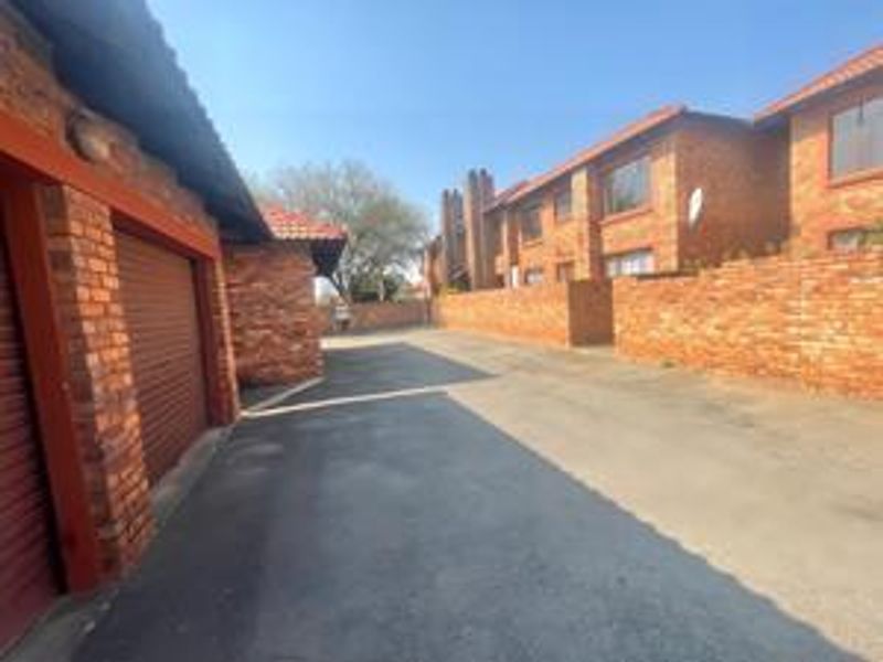 Exterior view of a cluster complex featuring face-brick facades, multiple garage units, and a paved driveway area.