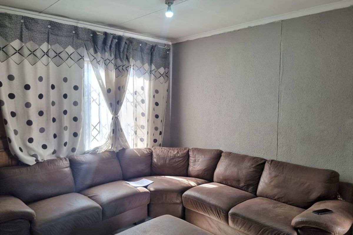 A living room featuring textured walls, a security gate on the window, and standard ceiling tiles.