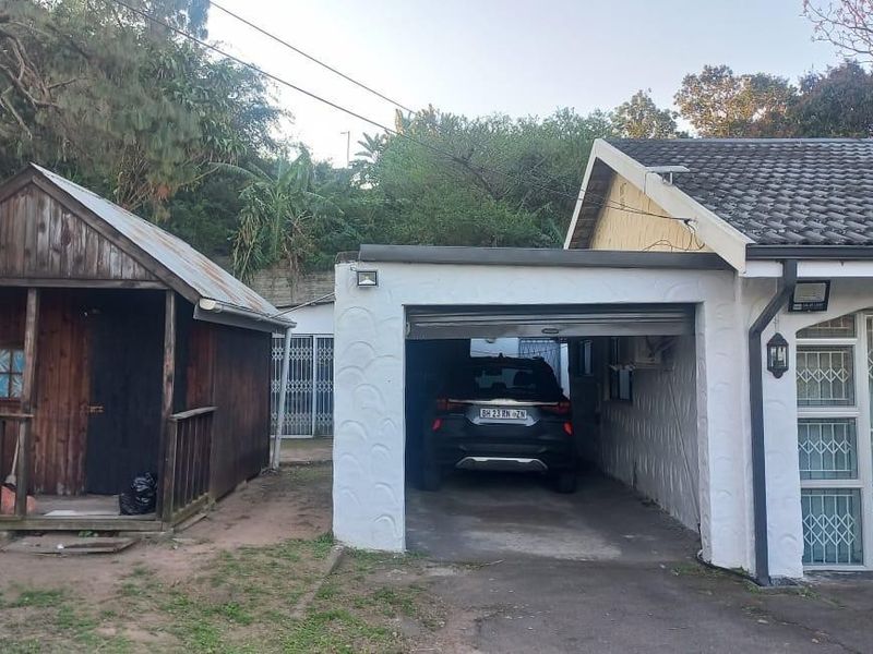 Front view of the property featuring a single garage, a separate wooden outbuilding, and security gates on the main dwelling entrance.