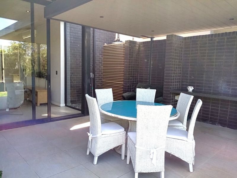 A covered outdoor patio featuring tiled flooring, dark brick walls, a built-in stone counter, and large sliding glass doors leading to the interior.