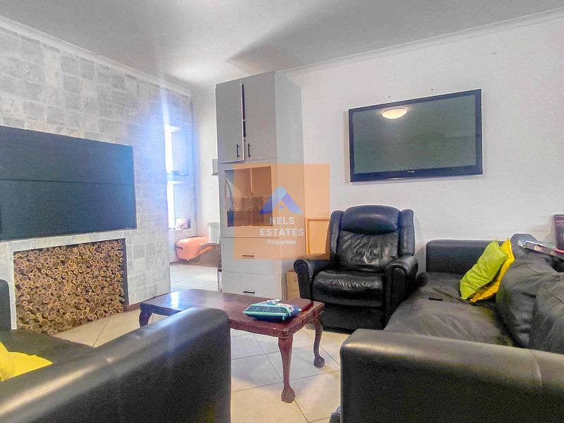 A living room featuring a stone-clad feature wall with a built-in fireplace and tiled flooring, offering a functional space for relaxation.