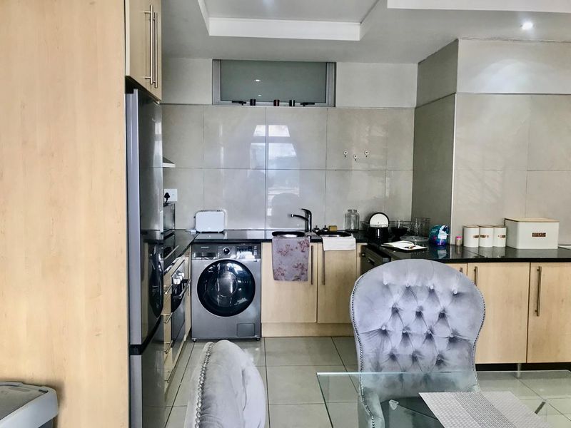 A functional kitchen featuring light wood cabinetry, granite countertops, tiled backsplash, and integrated laundry appliance space.