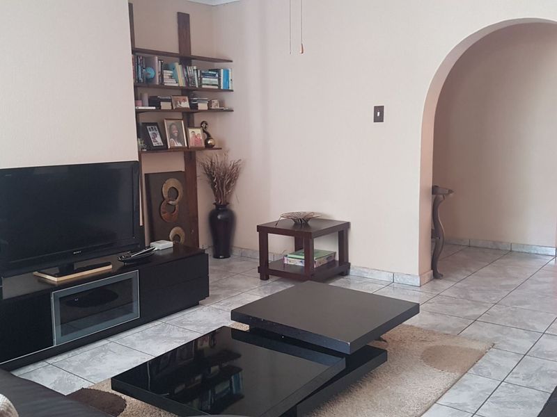 A living room featuring tiled flooring and a distinctive arched doorway leading to an adjacent area of the home.