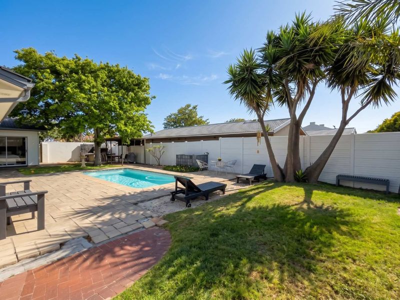 Outdoor pool area featuring a swimming pool, paved patio space, and landscaped garden with boundary walling.