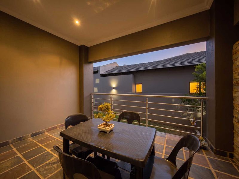 A covered patio featuring stone tile flooring, a stone feature wall, and a stainless steel balustrade, offering a pleasant outdoor living space.