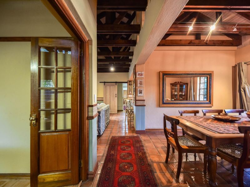 Open plan living and dining area featuring rustic exposed timber ceiling beams, terracotta floor tiles, and classic timber joinery throughout the space.
