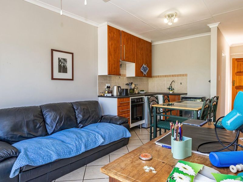 Open-plan living area featuring a compact kitchen with built-in cabinetry, oven, and tiled flooring, seamlessly integrated with the living space.