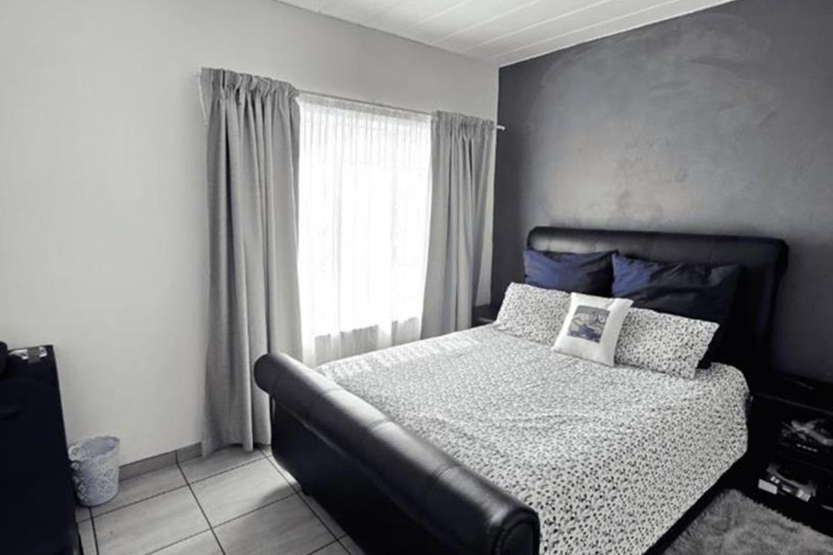 A bedroom featuring tiled flooring, a tongue and groove ceiling, and a dark accent wall, providing a neutral base for personalization.