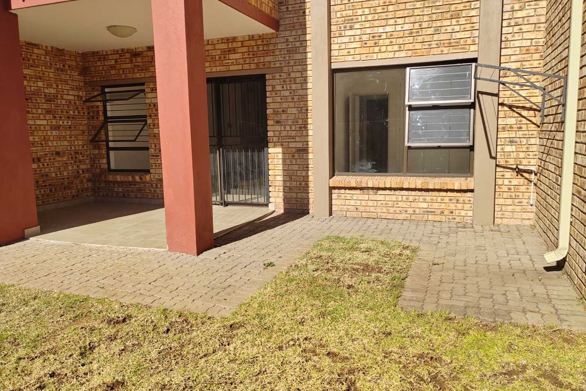 Rear view of the apartment featuring a paved patio area, brick exterior walls, and a small private garden space.