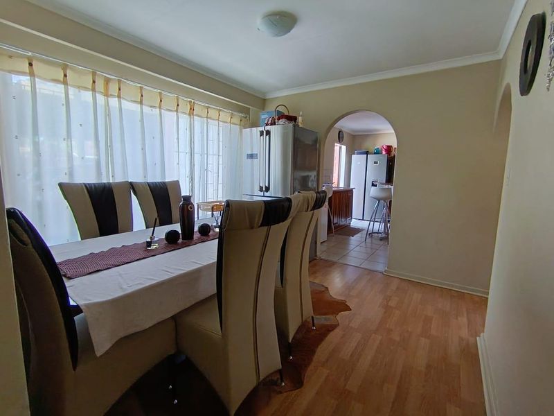 Dining room featuring laminate flooring and an arched entryway leading to the kitchen area.