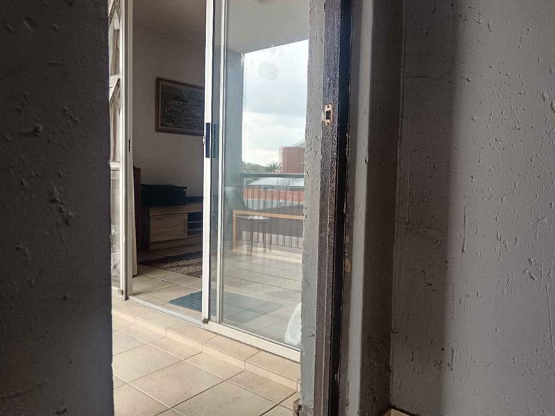 A view from a doorway onto a tiled balcony area, showing a sliding glass door and textured wall finishes.