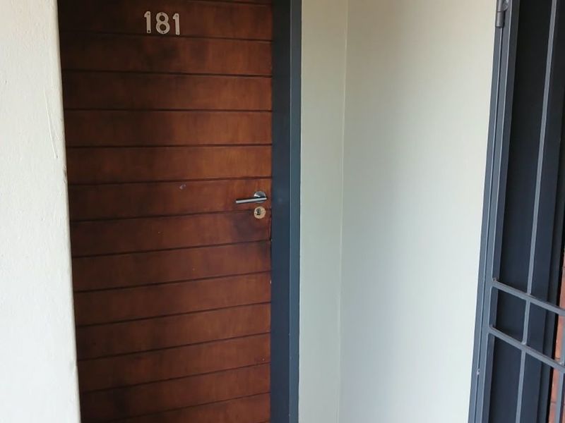 Apartment entrance featuring a wooden front door with unit number and a metal security gate.